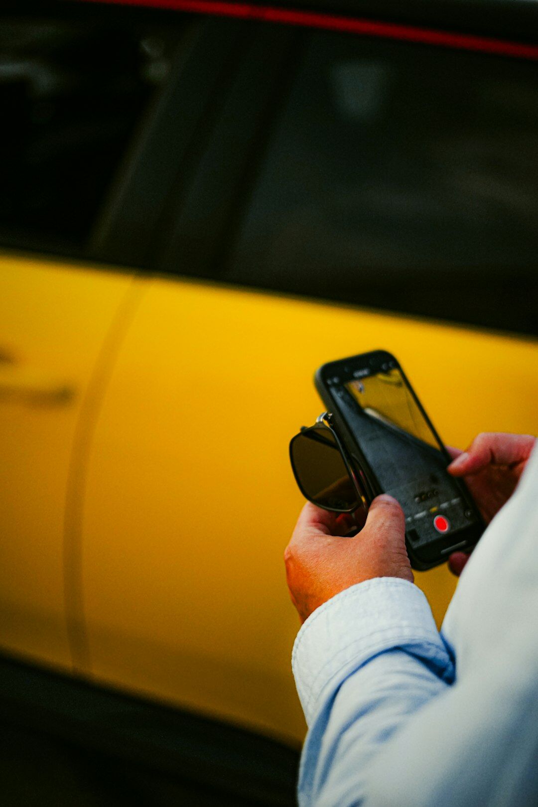 Person photographing a car with a smartphone to list it for sale